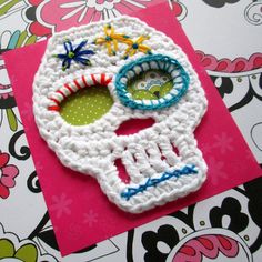 a crocheted sugar skull sitting on top of a pink card