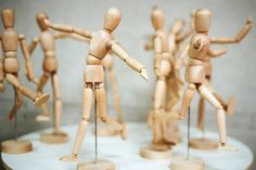 several wooden mannequins standing on top of a white cake with frosting