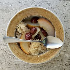 a bowl filled with fruit and nuts on top of a table next to a spoon