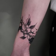 a woman's arm with a black and white flower tattoo on it, while the other hand is holding her wrist