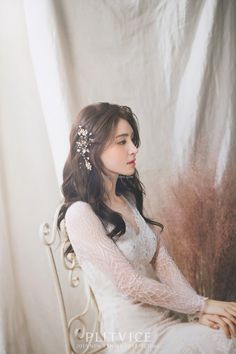 a woman sitting on top of a white chair next to a wall wearing a tiara