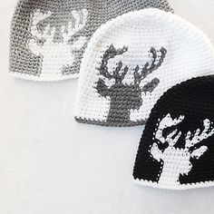 three crocheted hats with white and black deer heads on them, one is gray and the other is grey