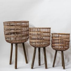 three wicker baskets sitting on top of wooden legs