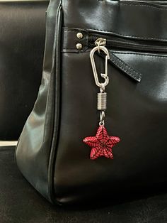 a black purse with a red star on the side and a metal keychain attached to it