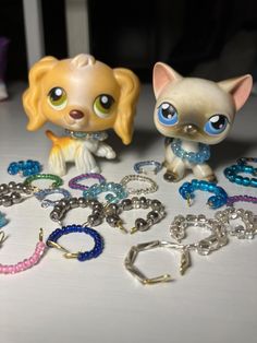 there are two little dogs next to each other on the table with bracelets and key chains