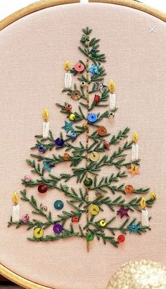 a cross stitch christmas tree with buttons on it's side and a gold ornament