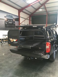 the back end of a black truck in a garage