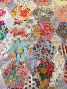 a patchwork quilt with colorful flowers and birds on it's sides, all made up of hexagons