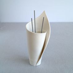 a white vase with three sticks sticking out of it