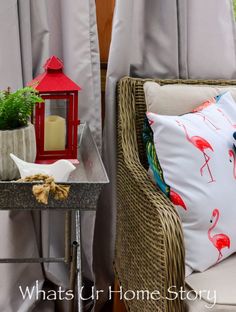 a chair with some pillows on it next to a small table and potted plants