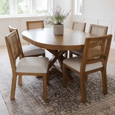 a dining room table with four chairs and a rug on the floor in front of it