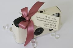 a small camera with a pink ribbon tied around it's neck and label on the front