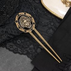 "This black jeweled hair fork is sure to add some elegance to your updo be it for a wedding, gala or night out on the town! It would also make a fantastic birthday, anniversary or Christmas gift for any bee lover. 💀 DESCRIPTION: This classy hair pin features a high domed black onyx cabochon that was hand set into an Victorian style setting. The gemstone was embellished with a large, highly detailed bee stamping that was layered over an ornate filigree with openwork detailing. The bee was blackened with patina to give it a rustic look. The setting was adorned with vintage glass cabochons from Swarovski® in Jet. The backing is a long u shaped hair pin. There is a slight curve in the end of one of the prongs. PLEASE NOTE: This piece is a bit on the heavy side and weights in at 1.7 oz or 50 g Onyx Hair, Jeweled Hair, Classy Hair, Brass Hair Pin, Bee Lover Gifts, U Shaped Hair, Jewelry Victorian, Victorian Hairstyles, Bridal Hair Piece