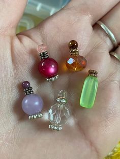 a person's hand holding five different colored glass bead charms in their palm