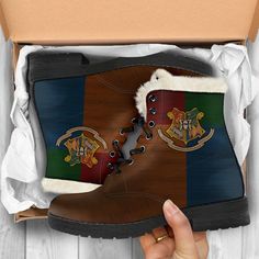 someone is holding up a pair of boots with hogwart's crests on them