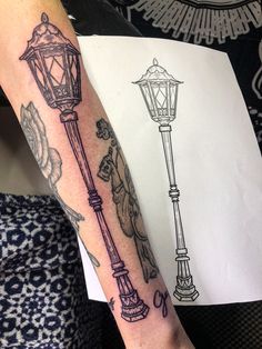 a person with a tattoo on their arm next to a lamp post