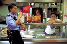 a police officer standing in front of a counter talking to a woman behind the counter