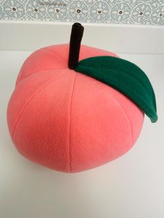 a stuffed peach with a green leaf on it