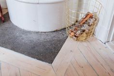 a white tub sitting next to a metal basket filled with food on top of a wooden floor