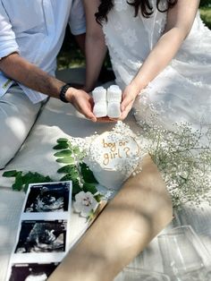 a man and woman cutting into a cake on top of a white sheet covered table