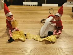 two elfs sitting on top of a wooden table next to chips and an iron