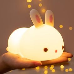 a hand holding a small light with an animal face on it's head and ears