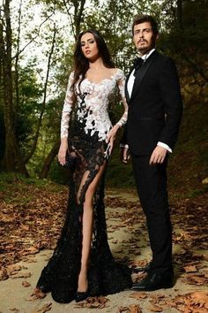 a man and woman in formal wear standing next to each other on a dirt path