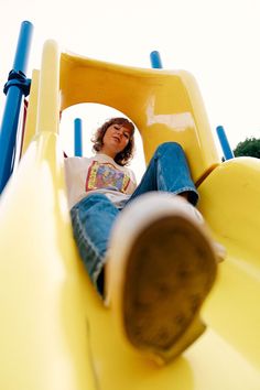 a woman sitting on top of a yellow slide