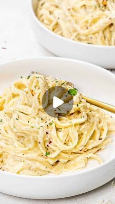 two white bowls filled with pasta on top of a table