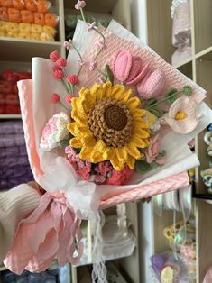 a bouquet of flowers sitting on top of a pink cloth covered hat in a store