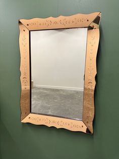 a mirror hanging on the side of a green wall next to a gray carpeted floor