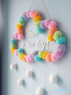 a colorful wreath with pom - poms hanging on the wall next to a sign that says have a nice day