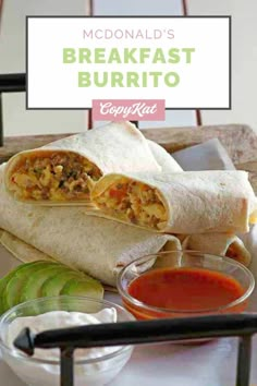 the breakfast burrito is cut in half and sitting on a plate with dipping sauce