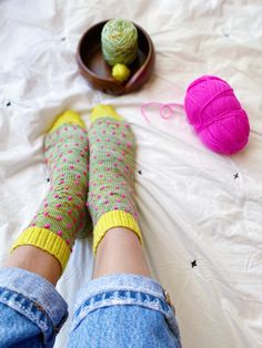 the legs of a person with socks and balls of yarn