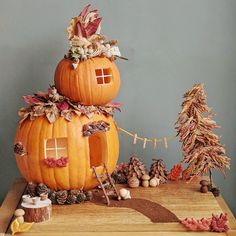 a pumpkin shaped house made out of leaves and pine cones on top of a wooden table