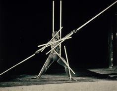 an old black and white photo of a man doing tricks on skis with poles