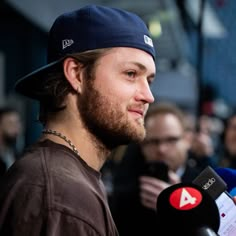 a man wearing a hat and holding a microphone in front of a group of people