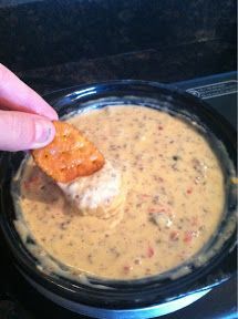 a hand dipping a cracker into a bowl of dip