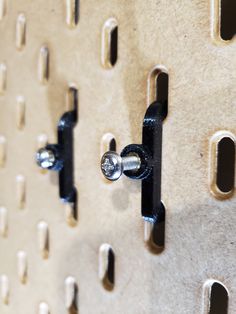 a close up of a metal hook on a wall with holes in the middle and two screws attached to it