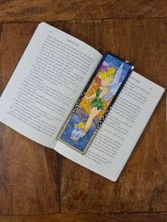 an open book with a stained glass design on the front and back cover, sitting on top of a wooden table