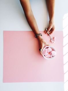 a woman is sitting at a table with pink flowers in a bowl on the floor