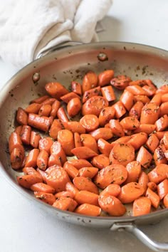 a pan filled with cooked carrots sitting on top of a white counter next to a napkin