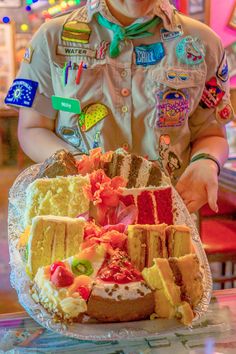 a boy in uniform is holding a cake on a plate with many different toppings