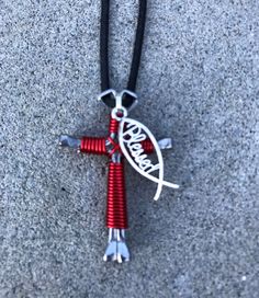 a red and silver necklace with a bird on it's back hanging from a black cord