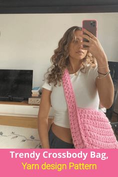 a woman taking a selfie in front of a mirror wearing a pink crocheted bag