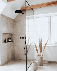 a bathroom with a tub, shower head and two planters in the corner on the floor