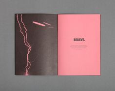 an open book with pink pages and lightning in the background on a gray table top