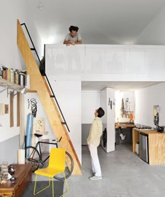 two people are standing on the stairs in a loft with an open floor plan and white walls