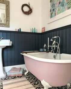 a pink bath tub sitting next to a white sink in a bathroom under a mirror