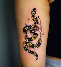 a woman's leg with a snake and flowers tattoo on the side of her thigh